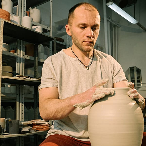 un homme qui fait un vase en céramique
