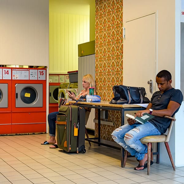 deux personnes patientent dans une laverie automatique