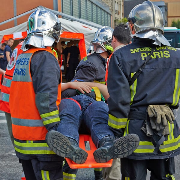 pompiers avec des vêtements ignifuges qui transportent un blessé