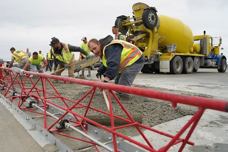 opérateurs qui étendent le béton sur un chantier